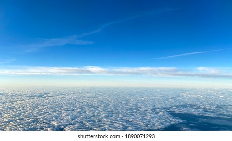An aerial view from an airplane window of clouds with bright blue skies.