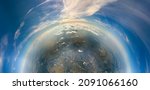 Aerial view from airplane window at high altitude of little planet distant city covered with layer of thin misty smog and distant clouds in evening
