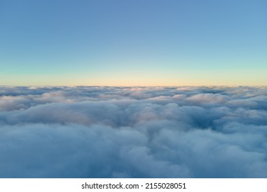 Aerial view from airplane window at high altitude of dense puffy cumulus clouds flying in evening - Powered by Shutterstock