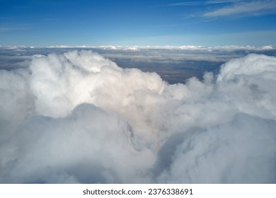 Aerial view from airplane window at high altitude of earth covered with white puffy cumulus clouds - Powered by Shutterstock