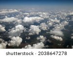 Aerial view from airplane window of white puffy clouds on bright sunny day.