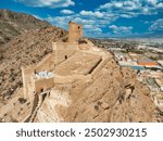 Aerial view of Alhama castle with large square keep restored using concrete and Iberian settlement ruins in Southern Spain Murcia province.