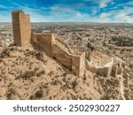 Aerial view of Alhama castle with large square keep restored using concrete and Iberian settlement ruins in Southern Spain Murcia province.