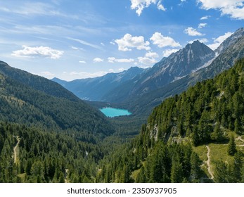 Aerial view of alpine lake Lago di Anterselva (Antholzer See) as seen from Passo Stalle (Staller Pass) in a Dolomite mountain valley with green pine forest 