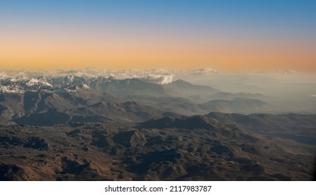 Aerial View Of Alps. Flying Over Alps. Amazing View On Mountain. Sunset. Aerial View From Airplane Flying Above Clouds. Beautiful Aerial Landscape View Of The Mountains