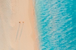 Aerial View Of Amazing Beach With Couple Walking In Sunset Light Close To Turquoise Sea. Top View Of Summer Beach Landscape, Romantic Inspirational Couple Vacation, Romantic Holiday. Freedom Travel