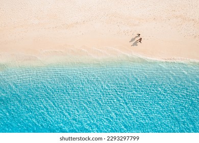 Aerial view of amazing beach with couple walking in sunset light close to turquoise sea. Top view of summer beach landscape, romantic love couple vacation, romantic holiday. Freedom leisure activity - Shutterstock ID 2293297799