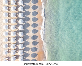 Nhìn từ trên không của bãi biển tuyệt vời với ô dù màu trắng và biển màu ngọc lam vào lúc hoàng hôn. Biển Địa Trung Hải, Sardinia, Ý.
