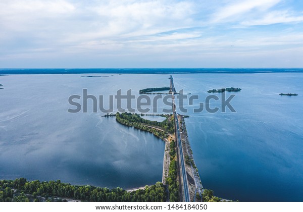 Aerial view of the\
amazing big river with bridge and dam under beautiful cloudy blue\
sky. Europe, Ukraine, Kremenchuk Reservoir,  Dnieper or Dnipro\
River. Summer sunset\
time.