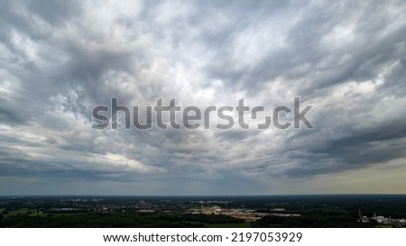 Aerial view amazing sunset over of the suburbs with the city under dramatic rain cloud. Global warming effect black thunderstorm dramatic rain clouds, dramatic sky, shot by a drone. High quality photo