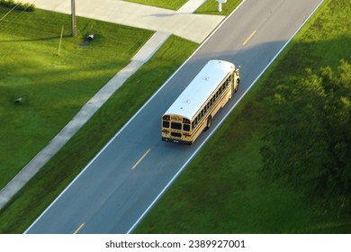 Aerial view of american yellow school bus driving on suburban street for picking up children for their lessongs in early morning. Public transportation in the USA - Powered by Shutterstock