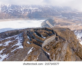 Aerial view of ancient fort ruins in the mountains next to frozen lake and dam - Shutterstock ID 2157145577