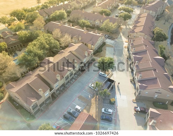 Aerial view\
apartment complex in Irving, Texas, USA. Covered parking lots, cars\
and green trees of multi-floor buildings at wintertime. Urban\
infrastructure and transportation\
concept