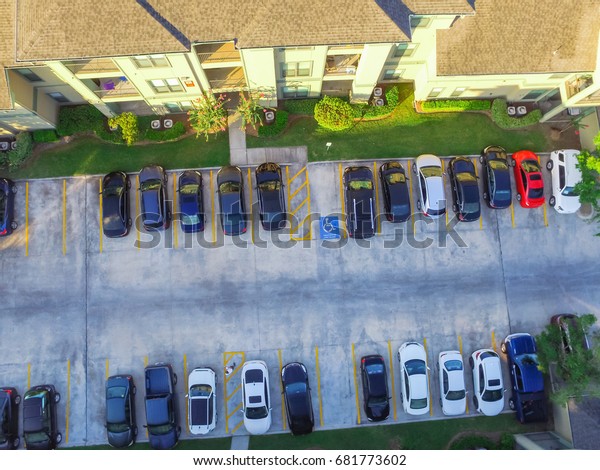 Aerial view of apartment garage with covered\
parking lots, cars and green trees at multi-floor buildings complex\
in Humble, Texas, US early morning. Urban infrastructure and\
transportation concept.