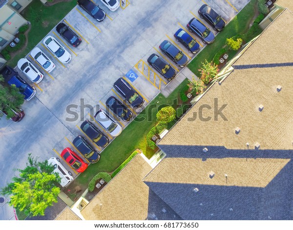 Aerial view of apartment garage with covered\
parking lots, cars and green trees at multi-floor buildings complex\
in Humble, Texas, US early morning. Urban infrastructure and\
transportation concept.