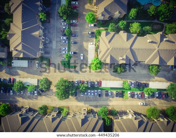 Aerial view of apartment garage with full of
covered parking, cars and green trees of multi-floor residential
buildings in Houston, Texas, US at sunset. Urban infrastructure and
transportation concept