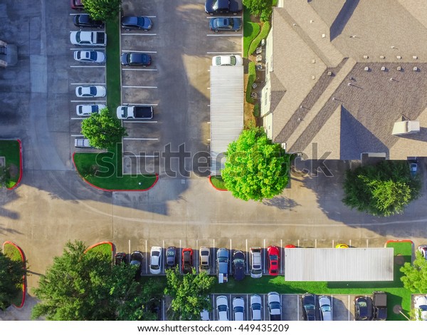 Aerial view of apartment garage with full of
covered parking, cars and green trees of multi-floor residential
buildings in Houston, Texas, US at sunset. Urban infrastructure and
transportation concept