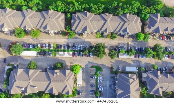 Aerial view of apartment garage with full of\
covered parking, cars and green trees of multi-floor residential\
building at sunset in US. Urban infrastructure and transportation\
concept. Panorama view.