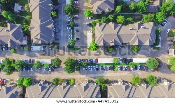Aerial view of apartment garage with full of\
covered parking, cars and green trees of multi-floor residential\
building at sunset in US. Urban infrastructure and transportation\
concept. Panorama view.