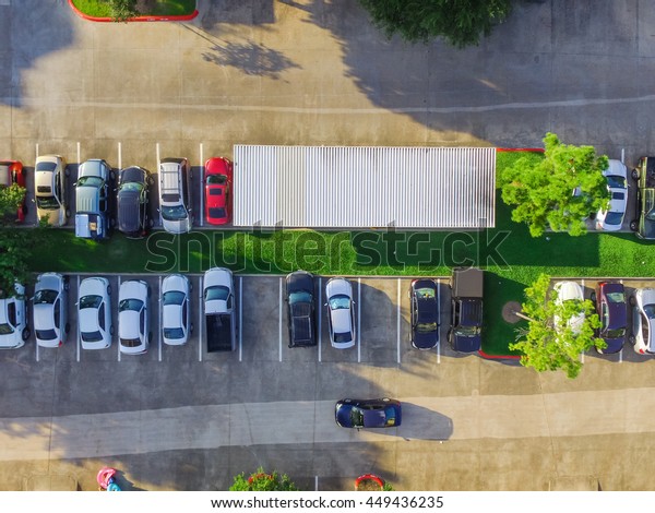 Aerial view of apartment garage with full of\
covered parking, cars and green trees of multi-floor residential\
buildings in Houston, Texas, US at sunset. Urban infrastructure and\
transportation concept