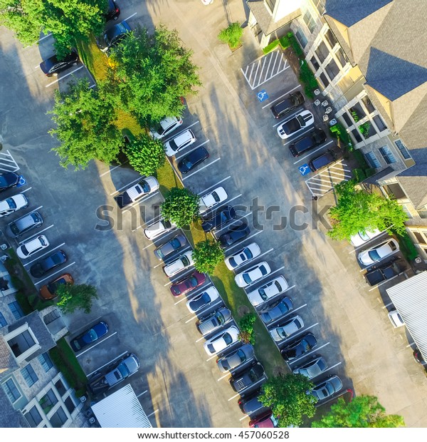 Aerial view of apartment garage with full of\
covered parking, cars and green trees of multi-floor residential\
buildings in Houston, Texas, US at sunset. Urban infrastructure and\
transportation concept