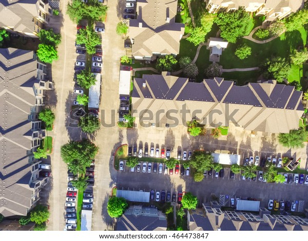 Aerial view of apartment garage with full of\
covered parking, cars and green trees of multi-floor residential\
buildings in Houston, TX in early morning. Urban infrastructure and\
transportation concept