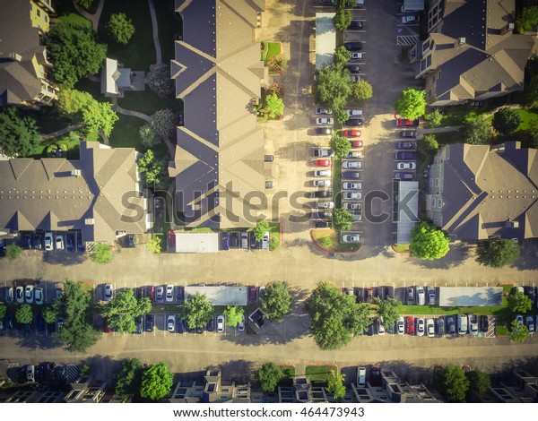 Aerial view of apartment garage with full of\
covered parking, cars and green trees of multi-floor residential\
building in early morning. Urban infrastructure and transportation\
concept. Vintage filter