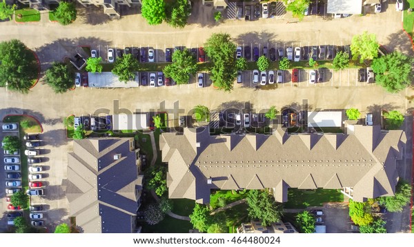 Aerial view of apartment garage with full of\
covered parking, cars and green trees of multi-floor residential\
building in early morning. Urban infrastructure and transportation\
concept. Panorama view.
