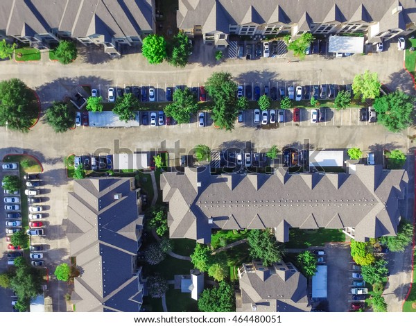 Aerial view of apartment garage with full of\
covered parking, cars and green trees of multi-floor residential\
buildings in Houston, TX in early morning. Urban infrastructure and\
transportation concept