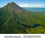 Aerial view of Arenal Volcano surrounded by lush green forest and a clear blue sky in Costa Rica