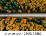 Aerial view of asphalt road with cars and colorful fall autumn forest in rural Finland.