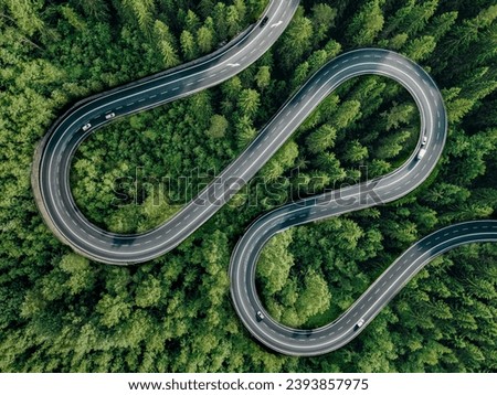 Aerial view of asphalt road with cars through green forest woods and mountain