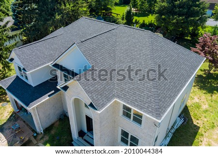 Aerial view of asphalt shingles construction site roofing the house with new window
