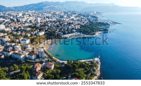 Aerial view of Bacvice Beach in Split, Croatia, showcasing the sandy beach, clear blue water, and vibrant atmosphere, with people enjoying the sunny weather and the stunning coastal landscape