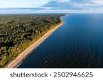 aerial view of the Baltic Sea coastline in Latvia, where dense forests meet the expansive blue waters and sandy beaches