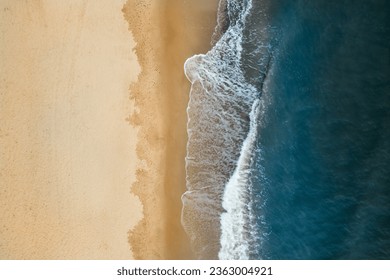 Aerial view of Baltic Sea shoreline with waves crushing sand beach during sunrise in the morning, bird's perspective, top down view, drone photography