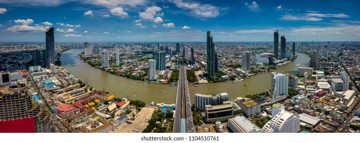 Aerial view of Bangkok skyline and skyscraper on Sathorn Road center of business in Bangkok downtown. Panorama of Taksin Bridge over Chao Phraya River Bangkok Thailand with blue sky and clouds.