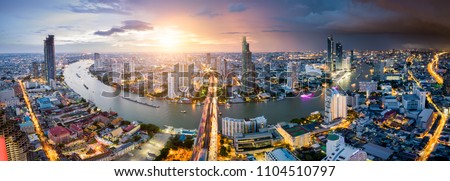 Aerial view of Bangkok skyline and skyscraper with light trails on Sathorn Road center of business in Bangkok downtown. Panorama of Taksin Bridge over Chao Phraya River Bangkok Thailand at sunset.