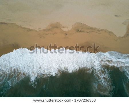 Foto Bild Luftaufnahme Panoramadrohne Blick auf den blauen Ozean Wellen, die am Sandstrand in Portugal erdrücken.