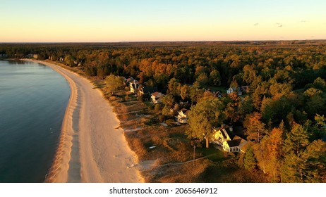 Aerial view of beachfront houses. Establishing shot of waterfront homes. Sunset sunrise sunlight,  Fall Autumn colorful trees. Midwest USA, Door county Wisconsin, lake Michigan.