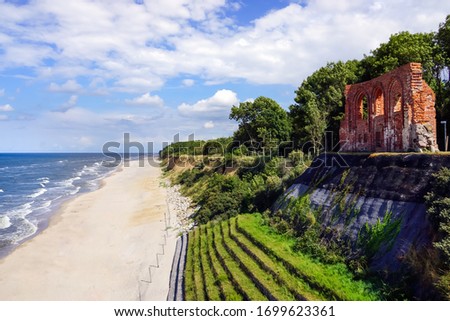 Aerial view of beautiful beach, sea and ruins of church in Trzesacz, Poland. Bright sunny day. Empty and closed due to covid 19 or coronavirus
