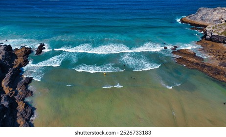 Aerial view of a beautiful beach with turquoise waters, gentle waves, and rocky formations. At Porth Beach, Cornwall, UK. - Powered by Shutterstock