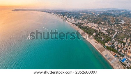 Aerial view of the beautiful coastline of the Albanian town of Golem with the city of Durres in the background. The photo shows a beautiful coastline with a sandy beach, umbrellas and hotels.