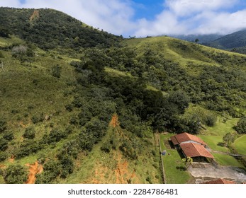 Aerial view of beautiful forest full of nature and pasture fields in Tremembé in Vale da Paraíba in São Paulo. Mountains and hills in sunny day. Lots of green and tropical vegetation. Drone.