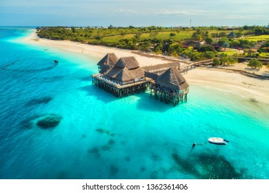 Aerial View Of Beautiful Hotel In Indian Ocean At Sunset In Summer. Zanzibar, Africa. Top View. Landscape With Wooden Hotel On The Sea, Azure Water, Sandy Beach, Green Trees, Boat. Luxury Resort