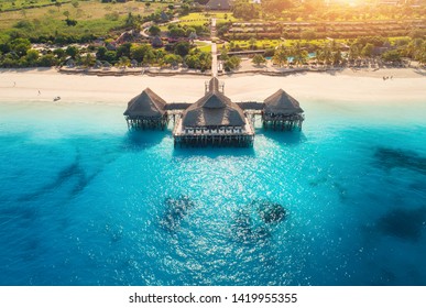 Aerial View Of Beautiful Hotel In Indian Ocean At Sunset In Summer. Zanzibar, Africa. Top View. Landscape With Wooden Hotel On The  Sea, Blue Water, Sandy Beach, Green Trees, Buildings. Luxury Resort