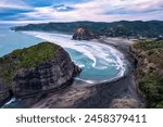 Aerial view of beautiful iconic Lion Rock and breaking wave on Piha beach in the evening at West coast of Auckland, New Zealand