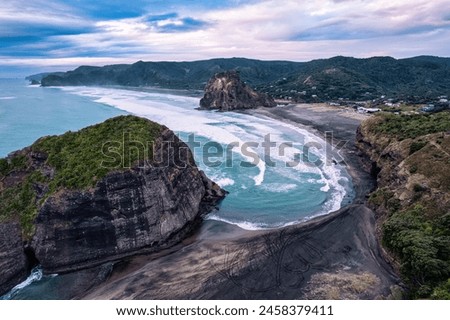 Aerial view of beautiful iconic Lion Rock and breaking wave on Piha beach in the evening at West coast of Auckland, New Zealand