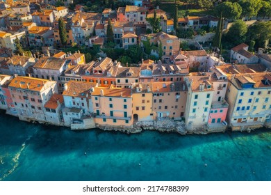 Aerial view of beautiful old houses with orange roofs at sunset in summer in Rovinj, Croatia. Top view of colorful architecture in old city and sea coast. Historical centre, buildings on the water