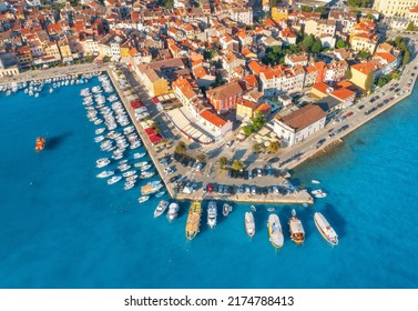 Aerial view of beautiful old houses with orange roofs, boats and yachts in dock at sunset in summer in Rovinj, Croatia. Top view of colorful architecture in old city and sea coast. Historical centre